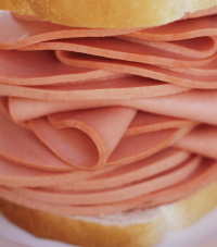 A large stack of baloney between two slices of white bread